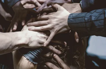 Various hands pushing down on a person's back.